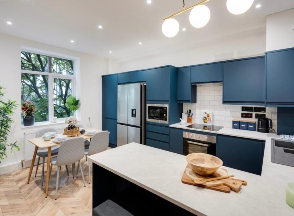 Bright modern kitchen with deep blue cabinetry,...