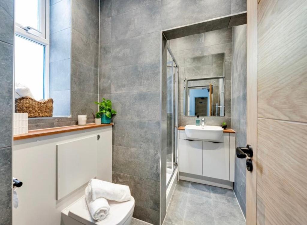 Contemporary bathroom with sleek grey tiles, a ...