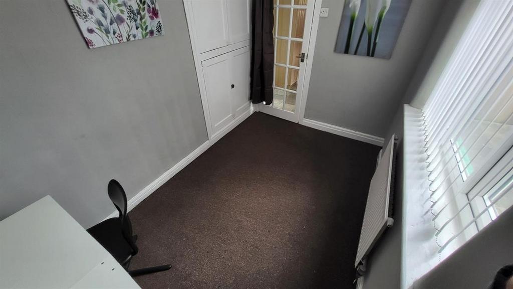 Neat single bedroom with a desk positioned by t...