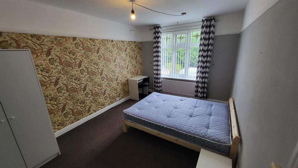 Bright double bedroom with a large window, patt...