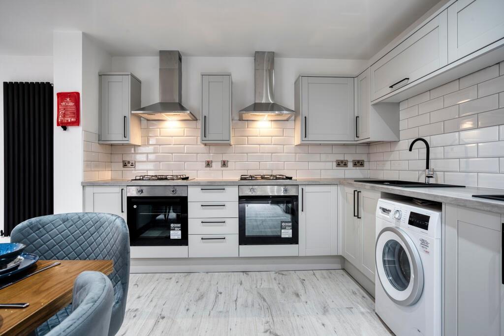 A modern, bright kitchen with white cabinetry, ...