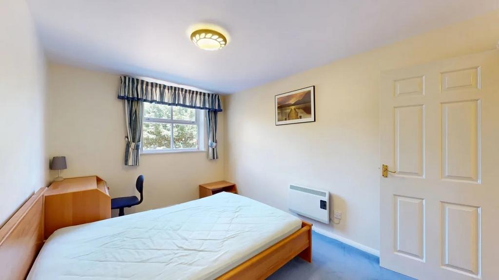 Bright, simply furnished bedroom with a double ...