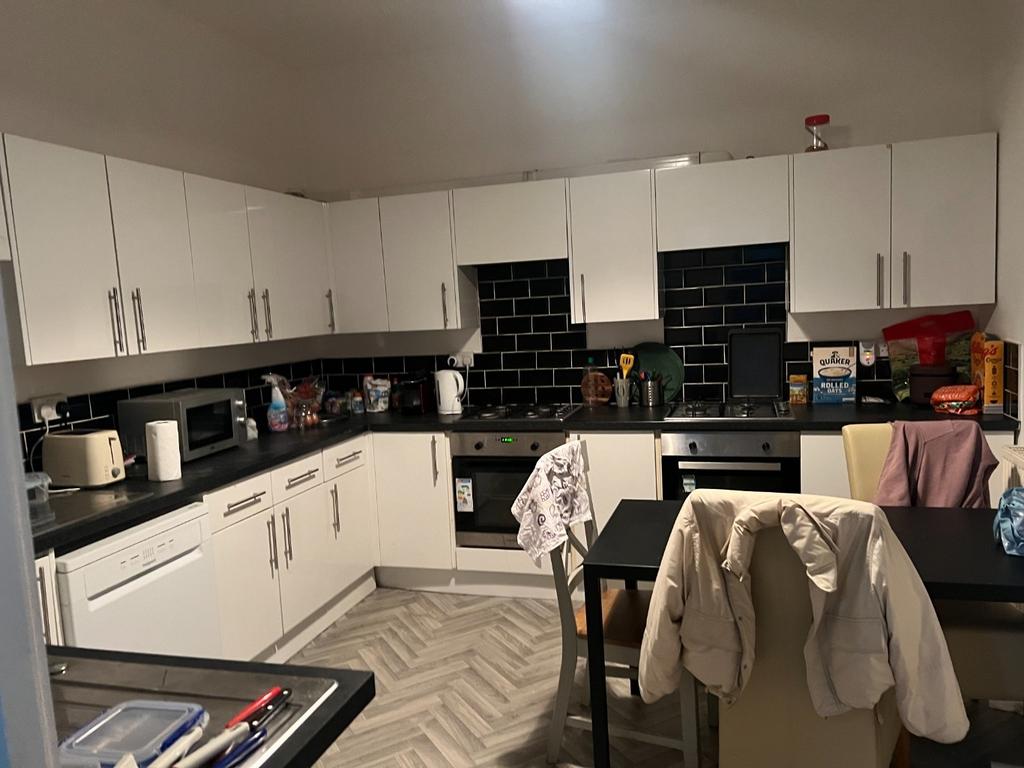 Modern fitted kitchen with white cabinetry, int...
