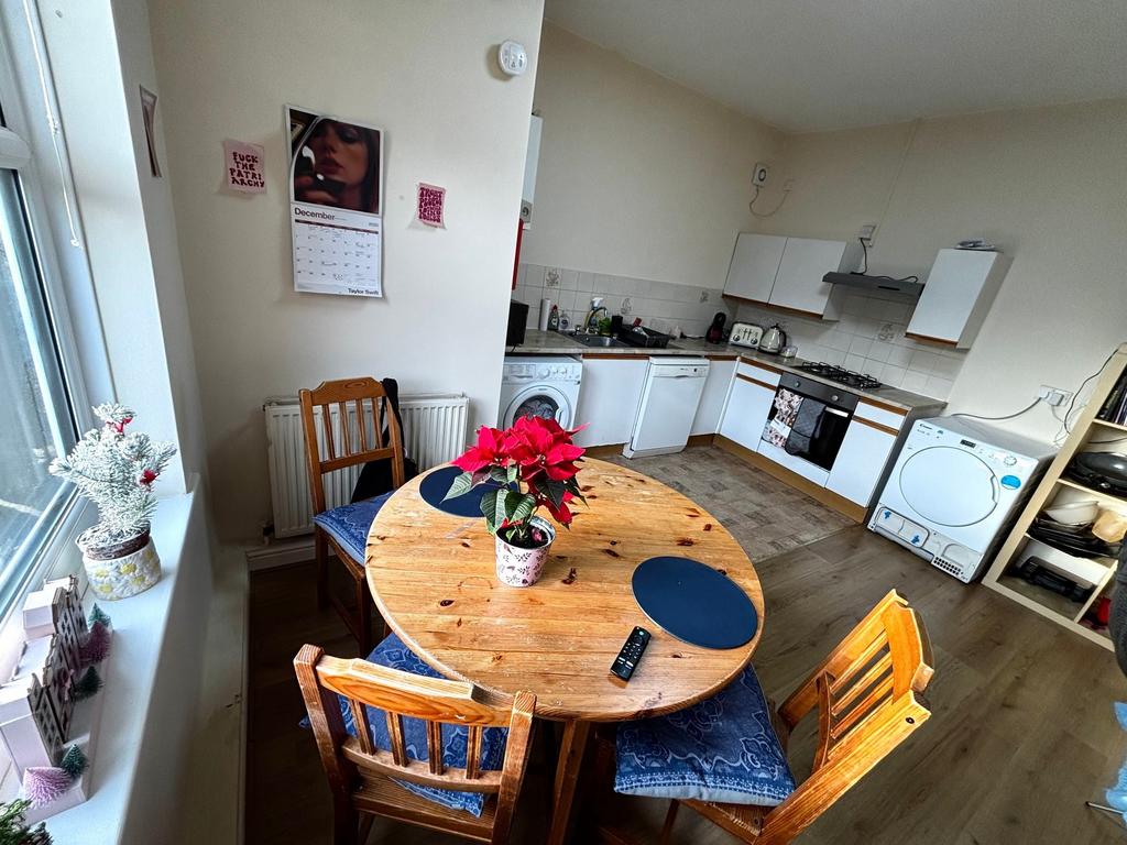 Bright open kitchen-diner with a round wooden t...