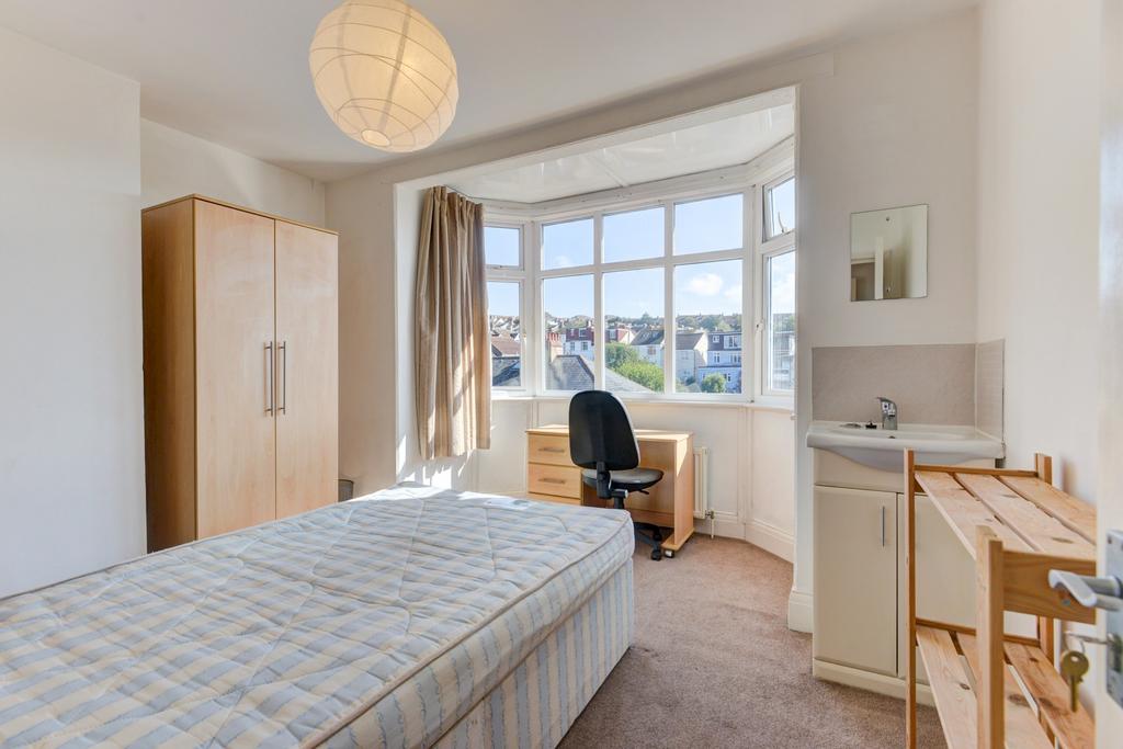 Bright, clean bedroom with a large bay window o...