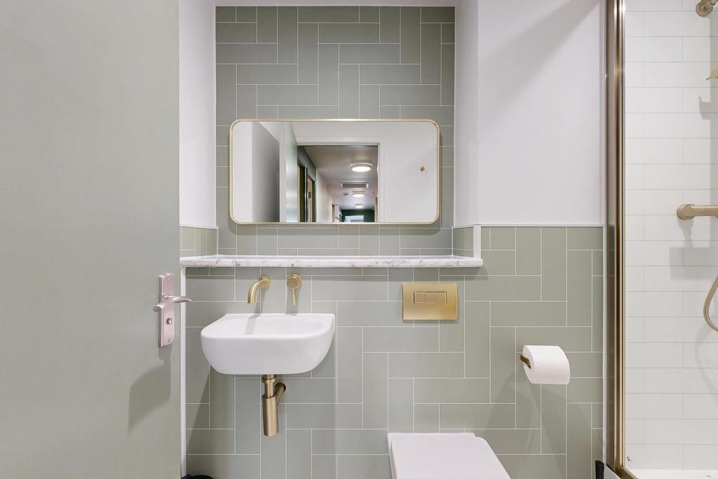 Modern bathroom with pale green tiled walls, a ...
