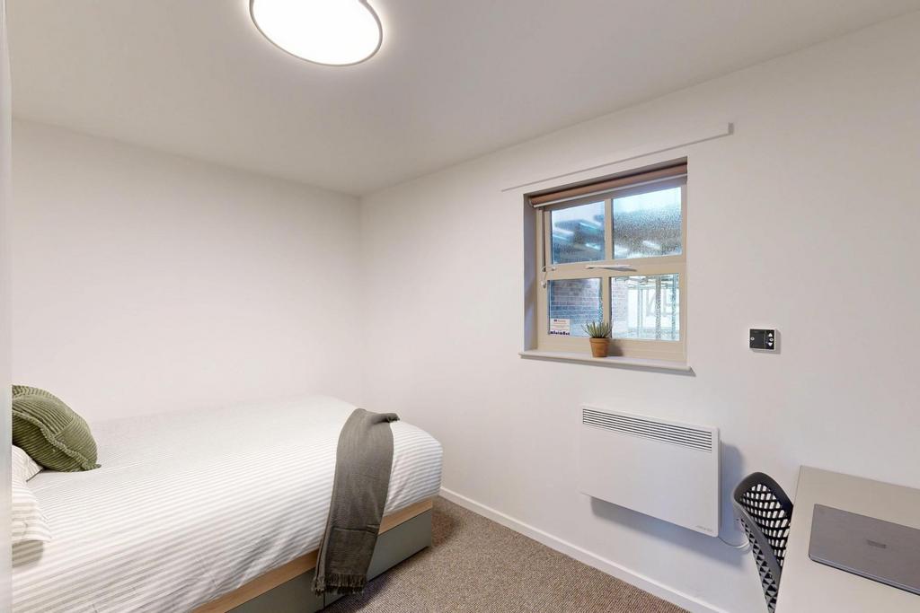 Bright, simply furnished bedroom with a comfort...