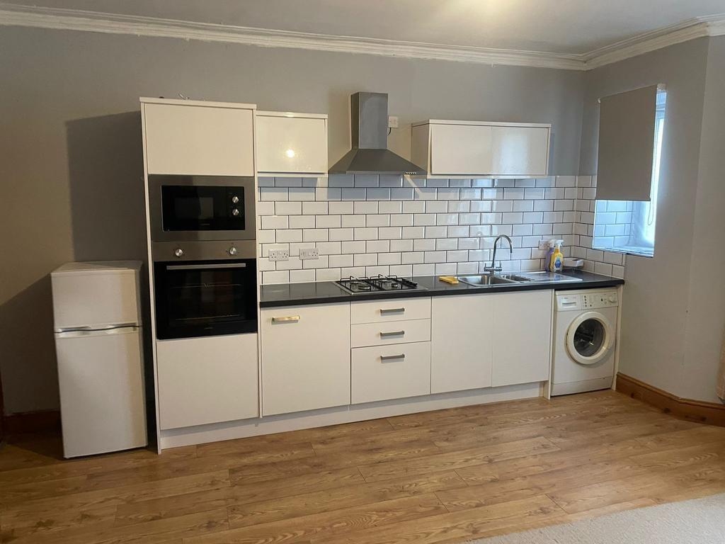 Modern fitted kitchen with white cabinetry, bla...