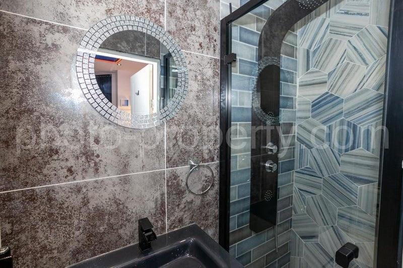 Contemporary bathroom with patterned tiled show...