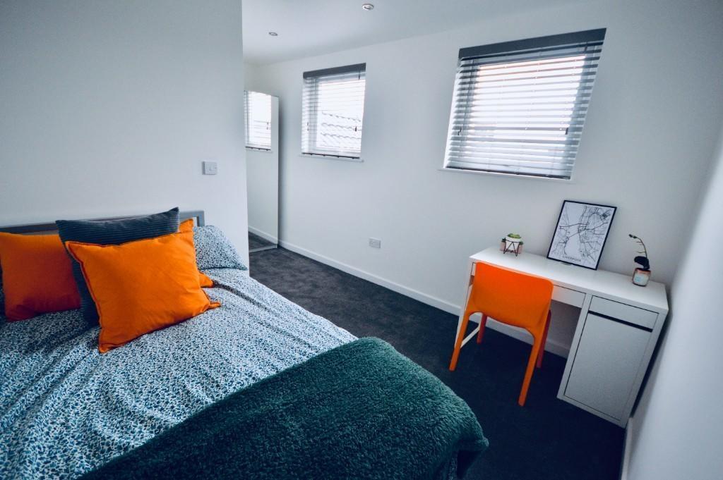 A bright and cozy bedroom featuring a neatly ma...