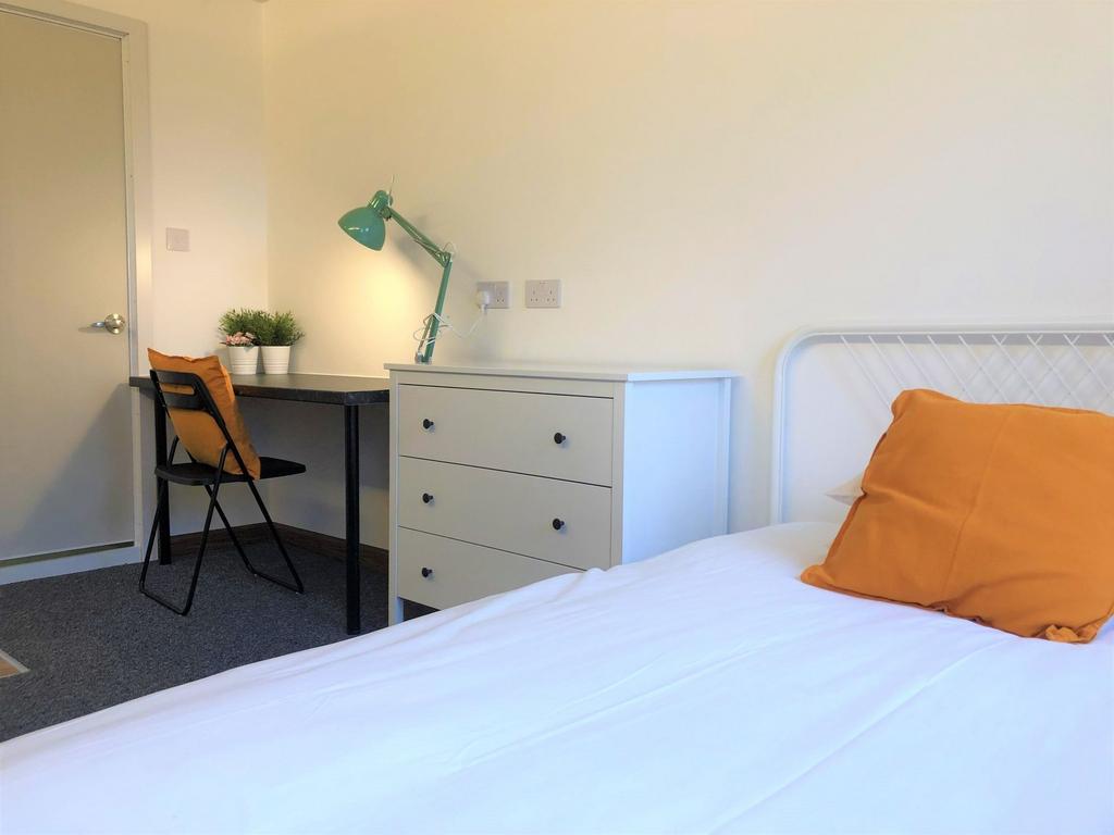 A neat and functional single bedroom featuring ...