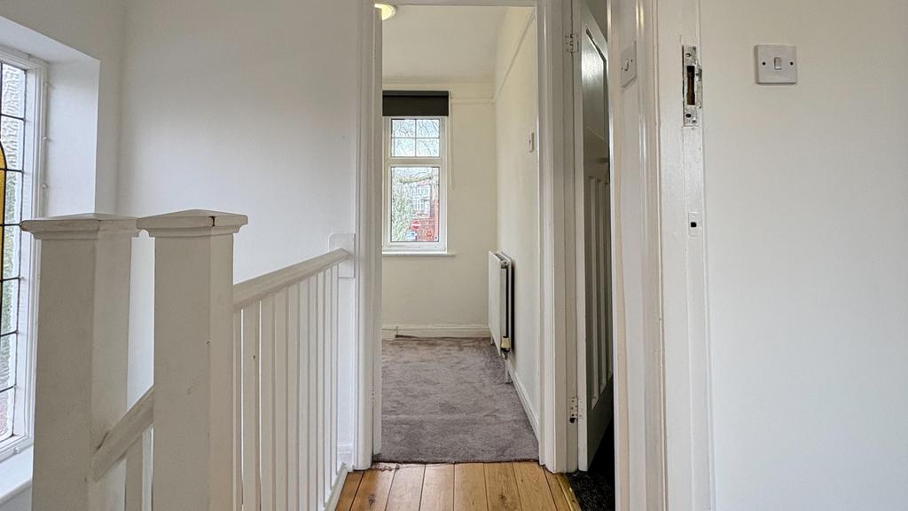 Bright upstairs hallway with white walls, woode...