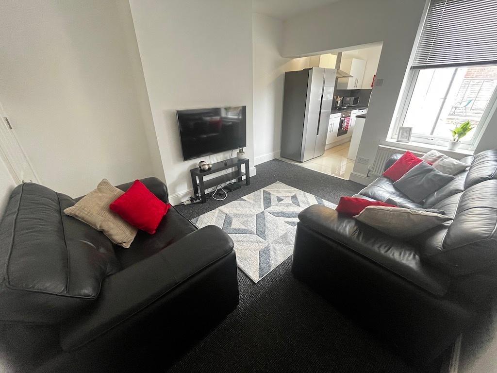Bright, modern living room with two black leath...