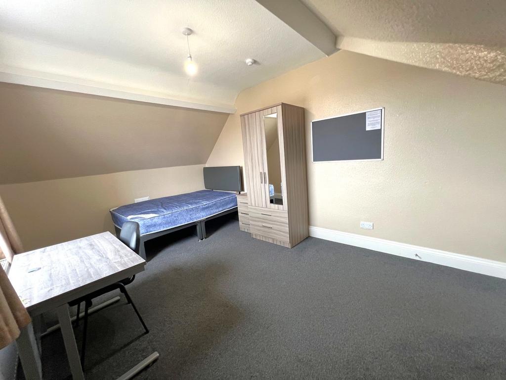 Bright attic-style bedroom with a single bed, d...