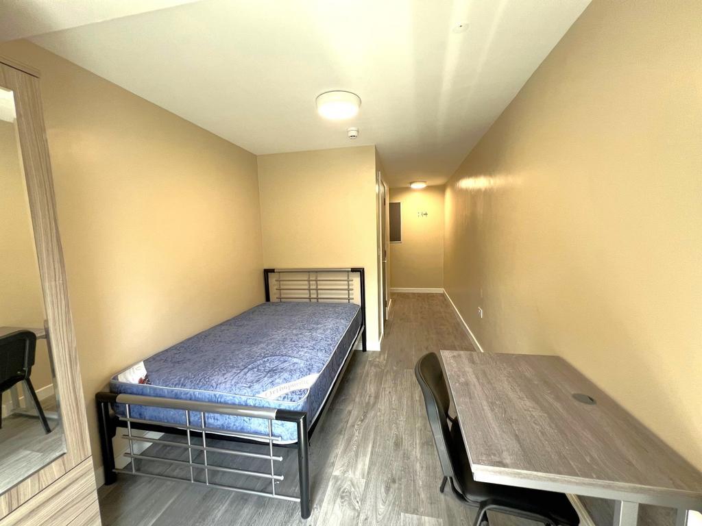 A cozy single bedroom featuring a metal frame b...