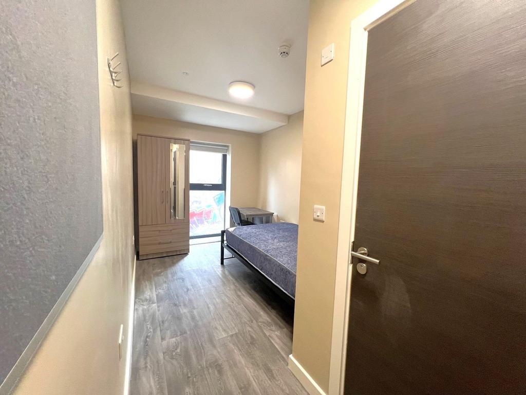 A clean, well-lit bedroom featuring a single be...