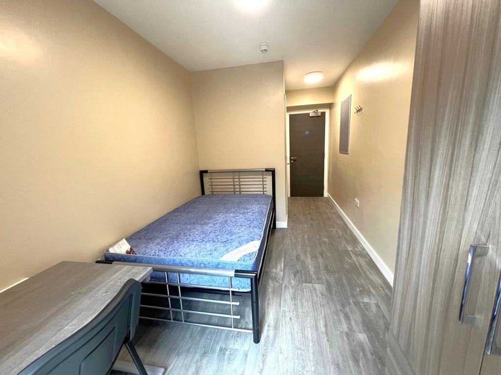 A compact student bedroom featuring a metal bed...