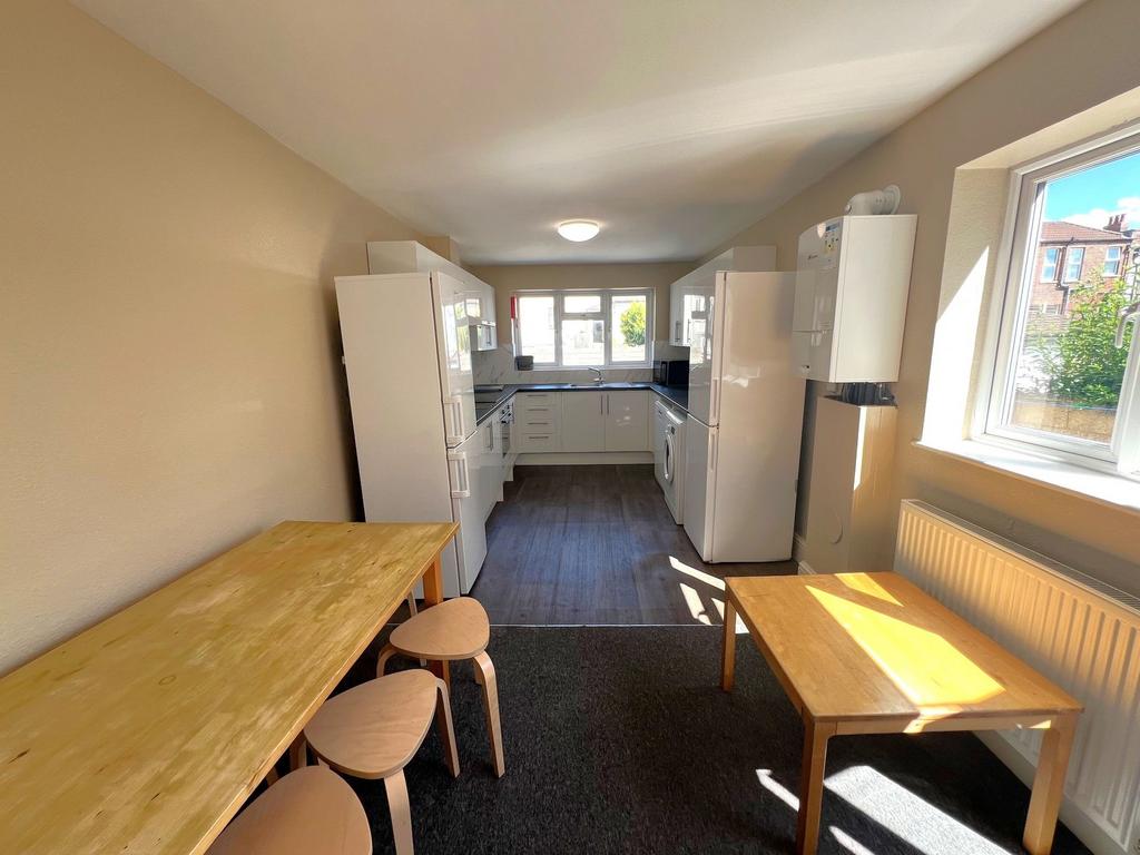 Bright galley-style kitchen with white cabinetr...