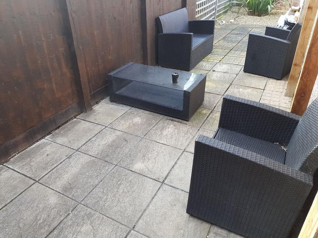 Private paved patio with modern rattan-style se...