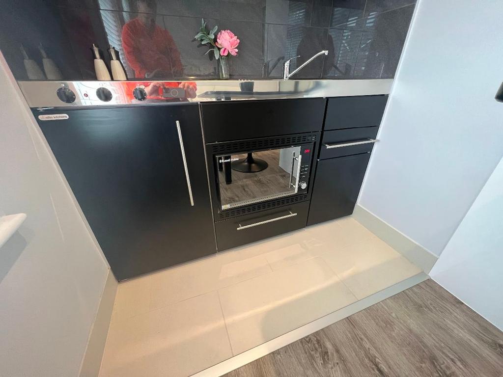 Modern compact kitchen with black cabinetry, in...