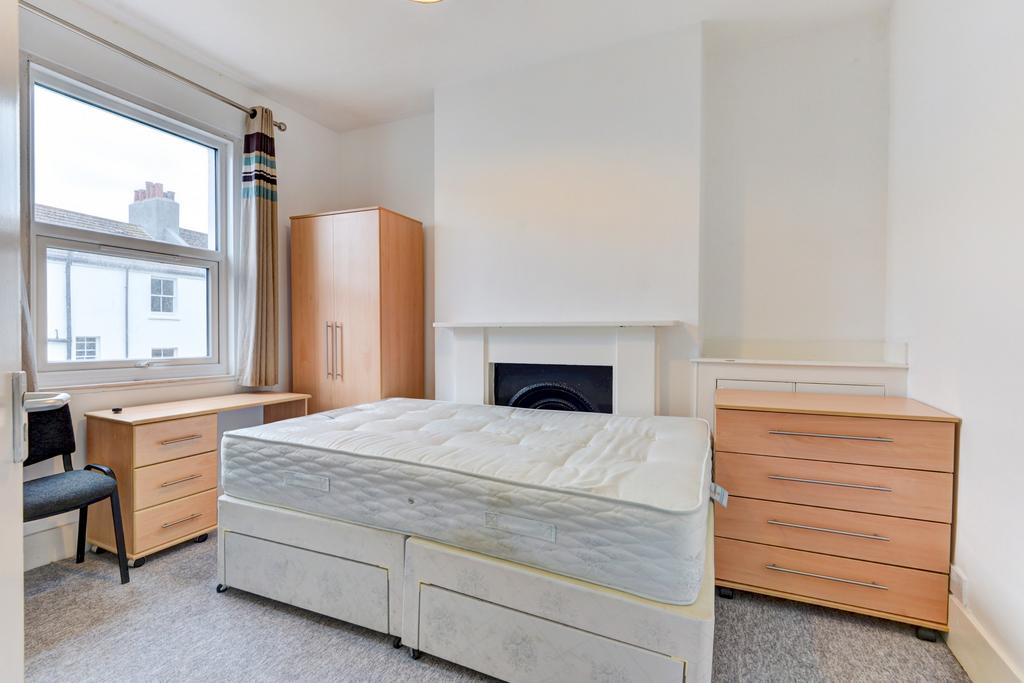 A bright, tidy bedroom featuring a large bed, a...