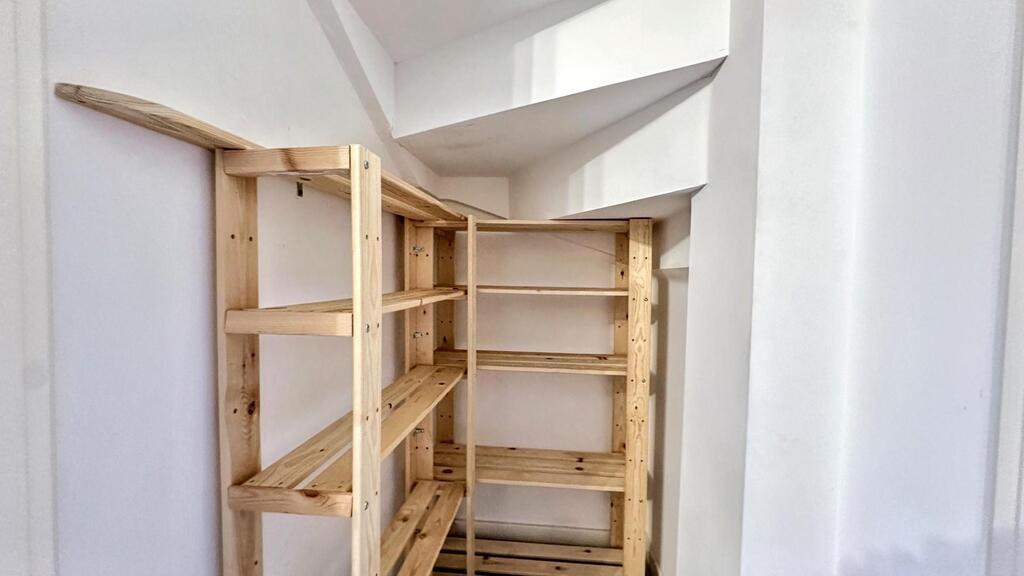 Well-lit storage nook with sturdy wooden shelvi...