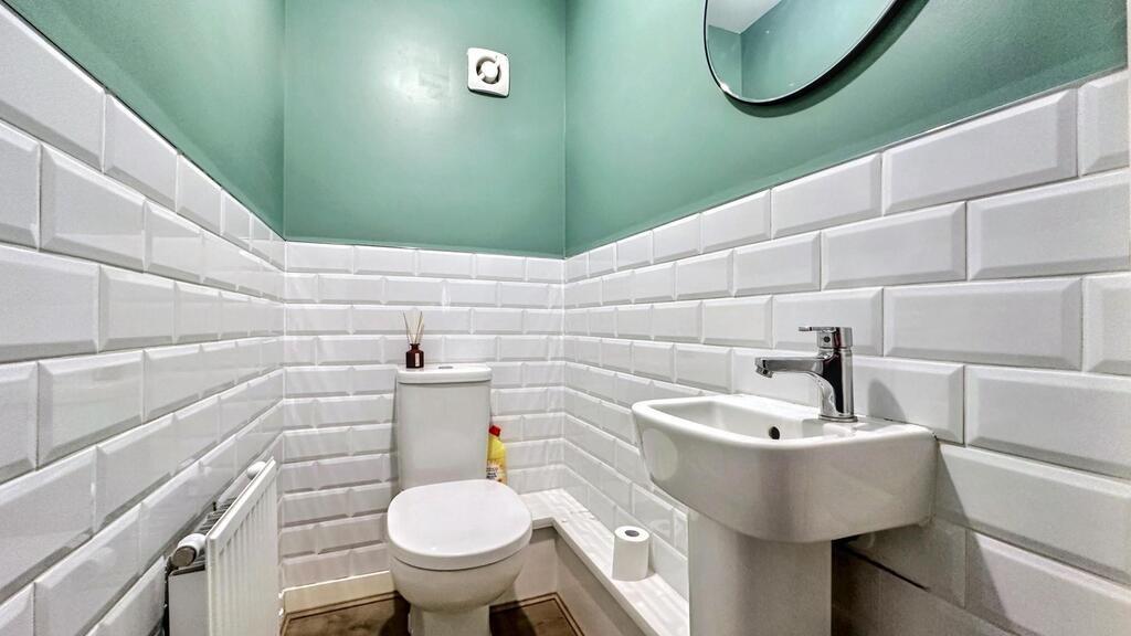 Bright, modern WC with white subway tiles, a co...