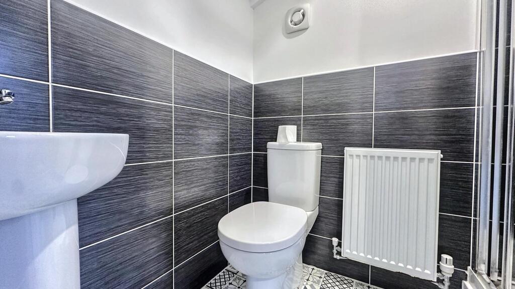 Bright, modern WC with contemporary tiled walls...