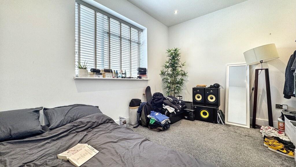 Bright double bedroom with a large window, neut...