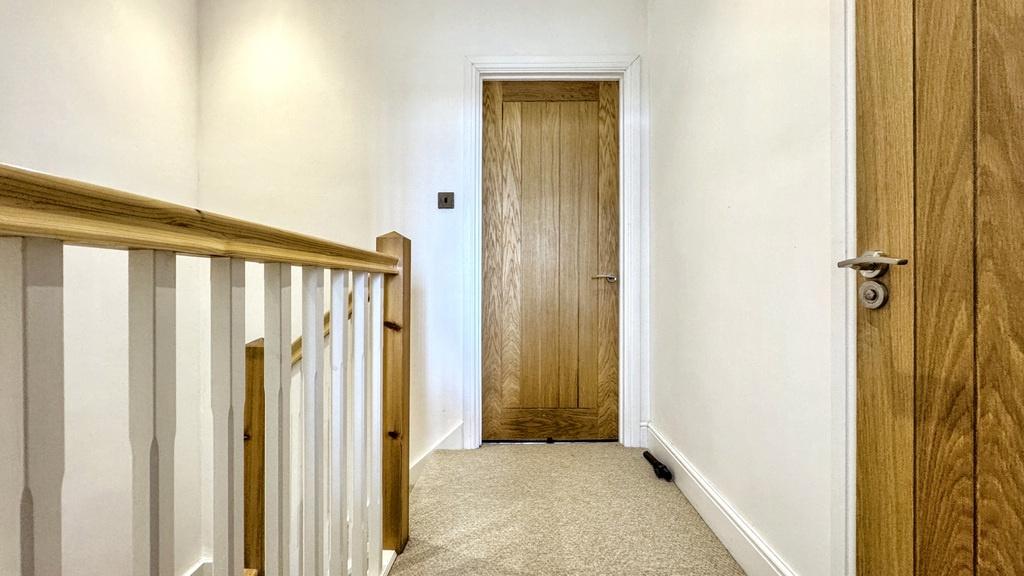Bright upstairs hallway with neutral carpet, wh...