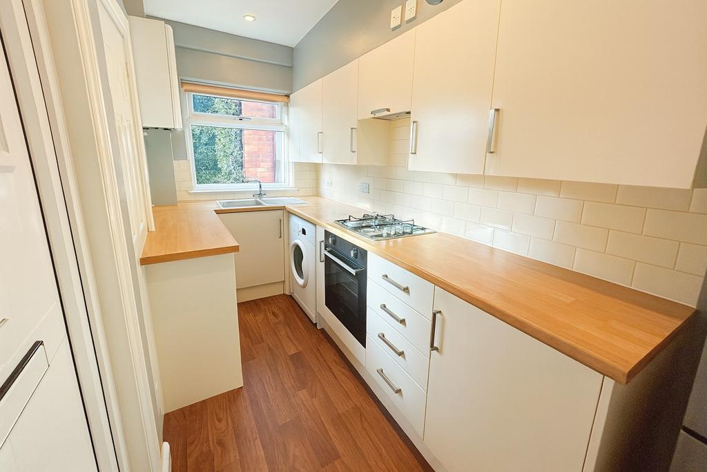 Bright modern galley kitchen with wooden counte...