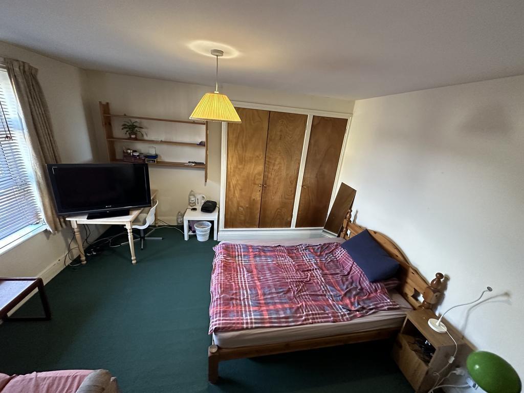 Bright double bedroom with a large window, buil...