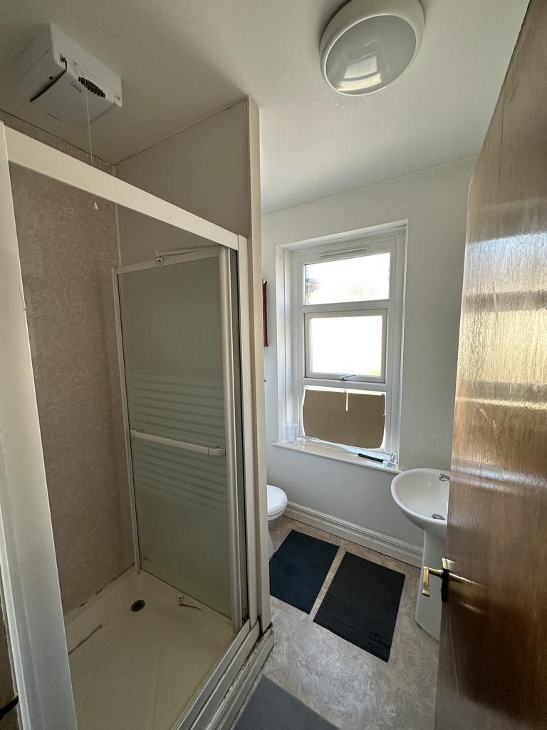 Well-lit bathroom with a corner shower cubicle,...