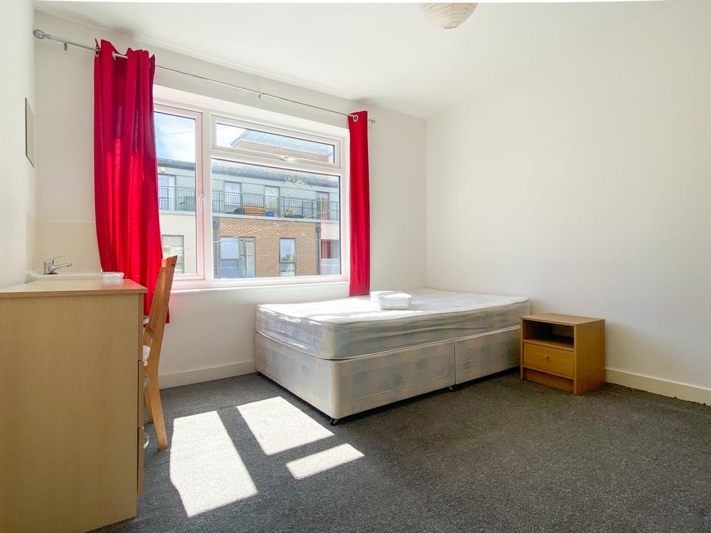 Bright, simply furnished bedroom with a large w...