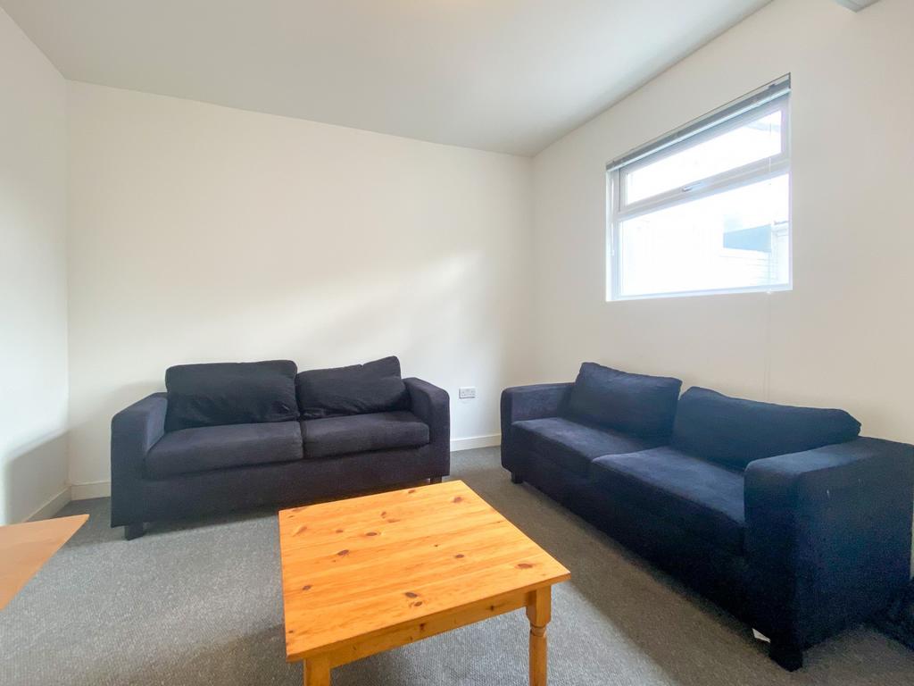Bright, simply furnished living room with two c...