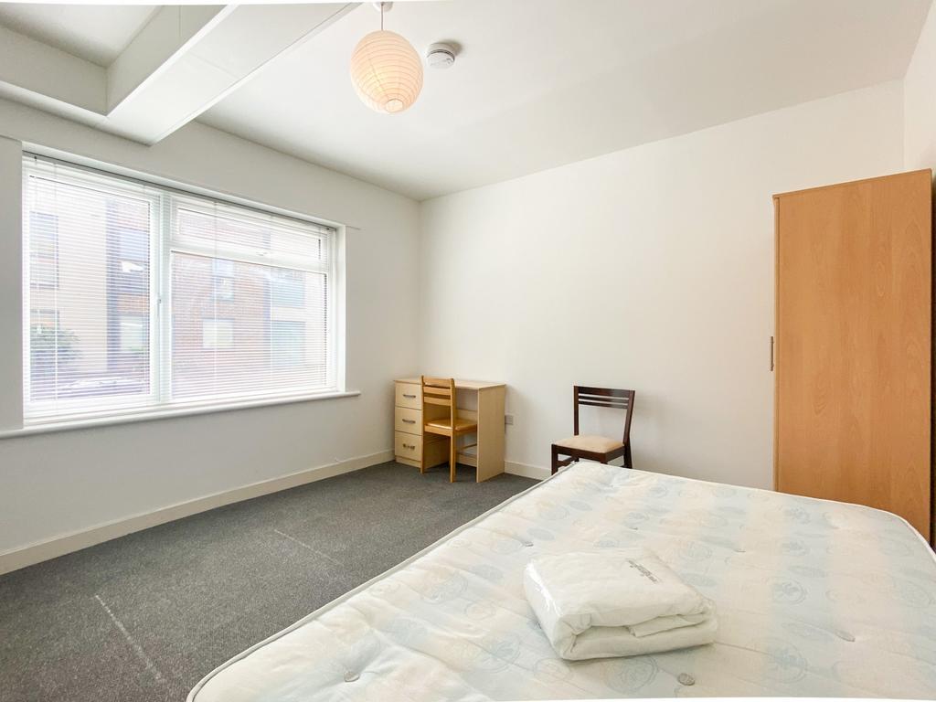 A bright and tidy single bedroom with a large w...