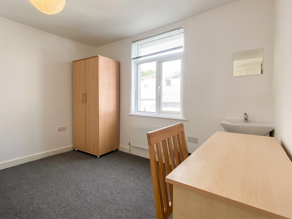 Bright, simply furnished bedroom with a desk, c...