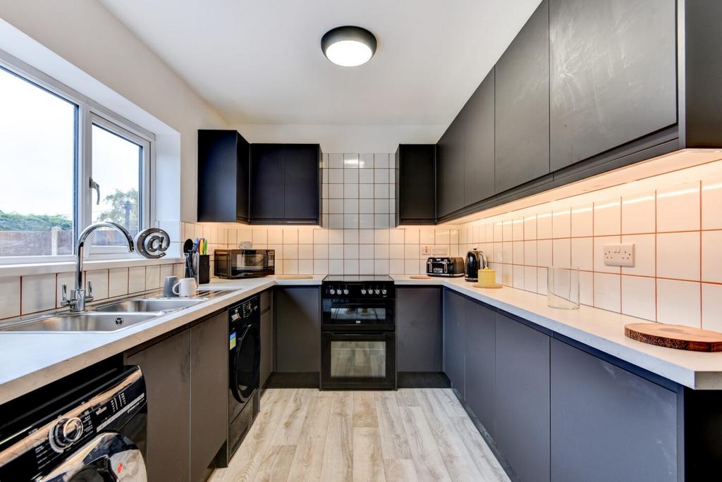 Modern U-shaped kitchen with dark cabinets, lig...