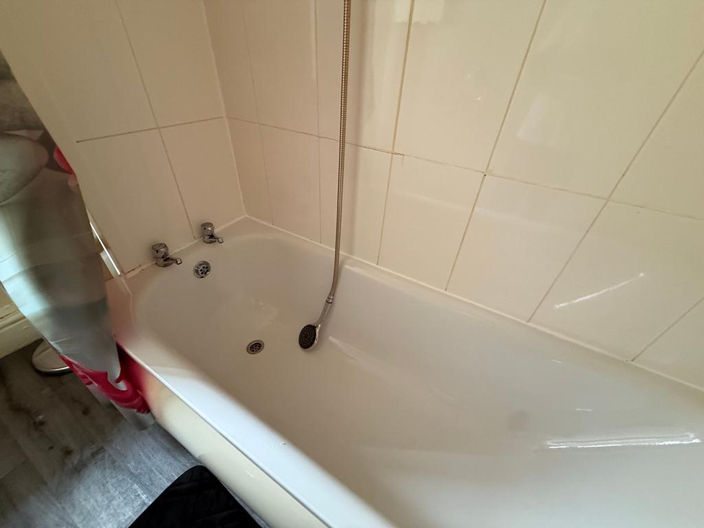 Bright bathroom with a clean white bathtub, til...