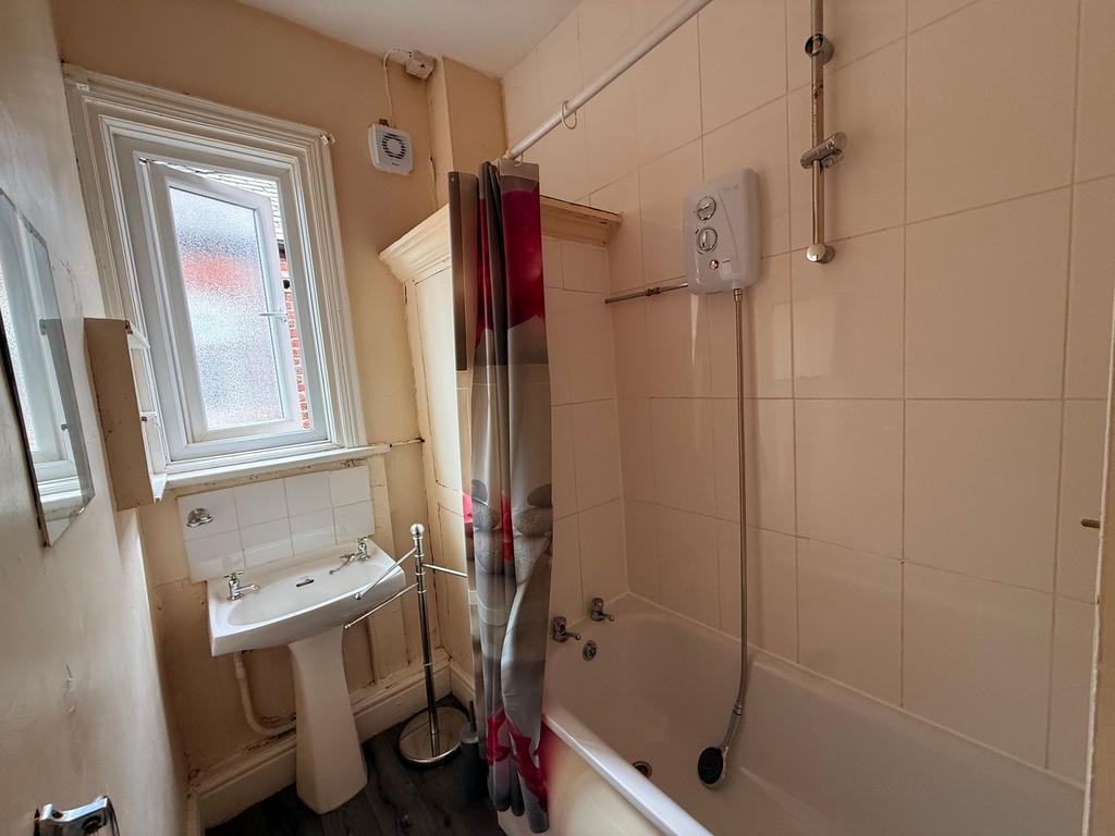 Bright bathroom with a tiled bath and shower, p...