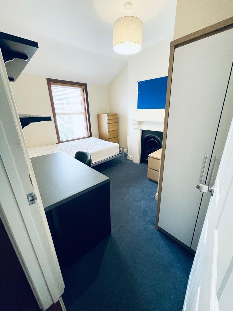 Bright, neatly furnished bedroom with a single ...