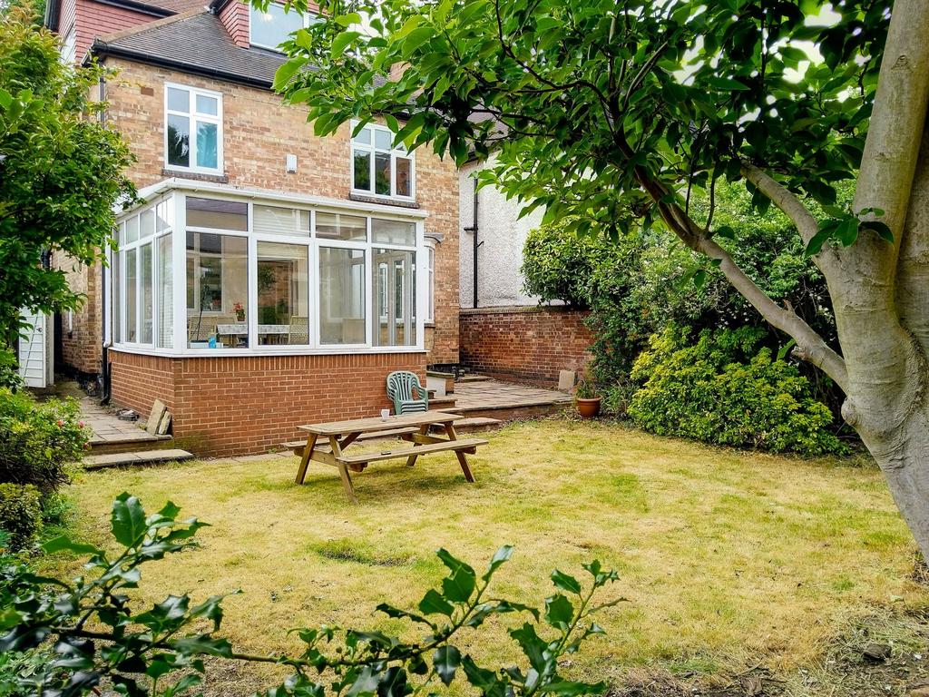 Sunny private rear garden with a lawn, mature t...