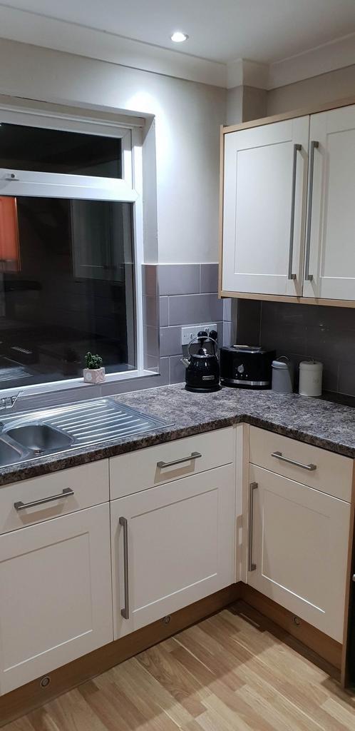 Bright, modern corner kitchen with white shaker...