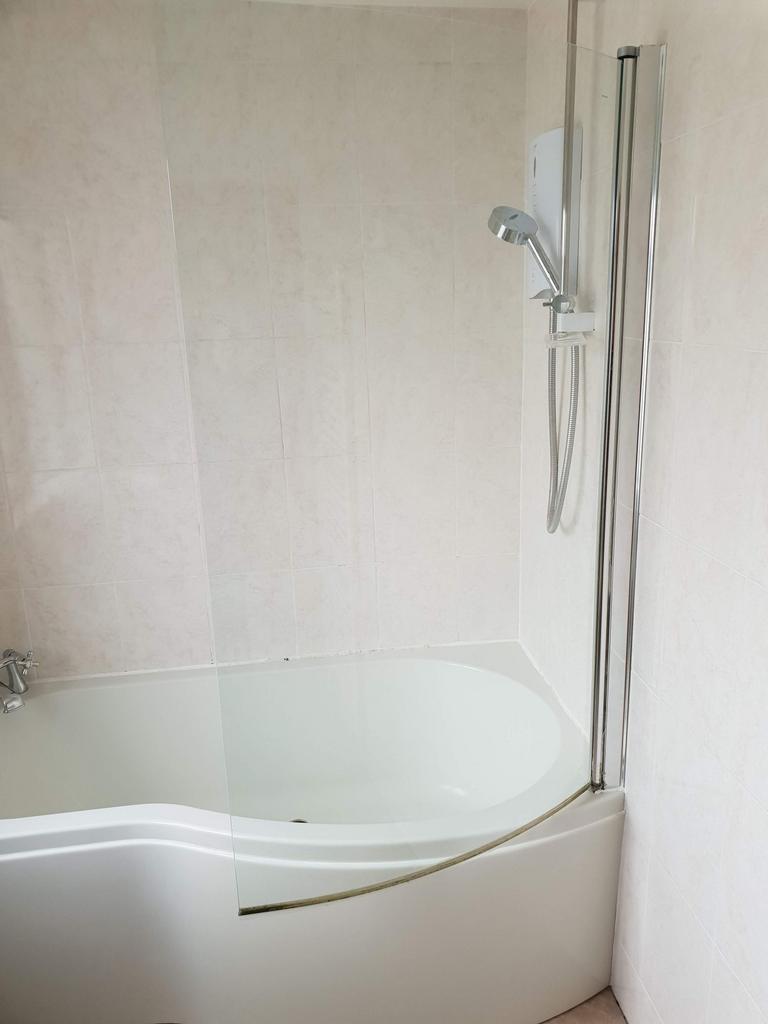 Bright, modern bathroom with a curved bath and ...