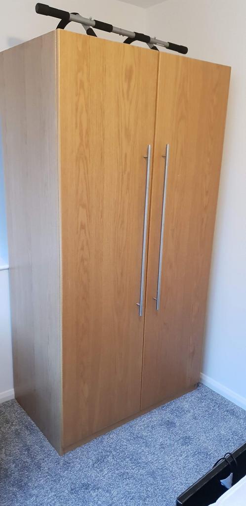 Tall wooden double-door wardrobe with long meta...
