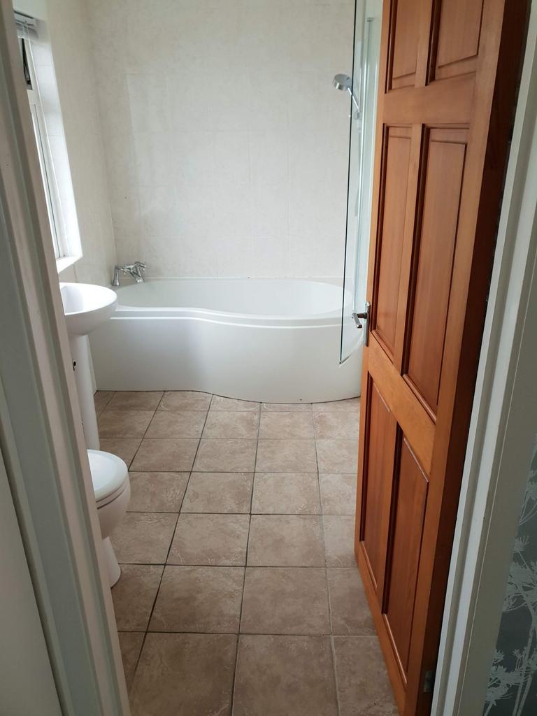 Bright, well-maintained bathroom with a curved ...