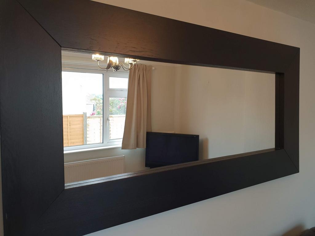 Bright living area with a large wall mirror tha...