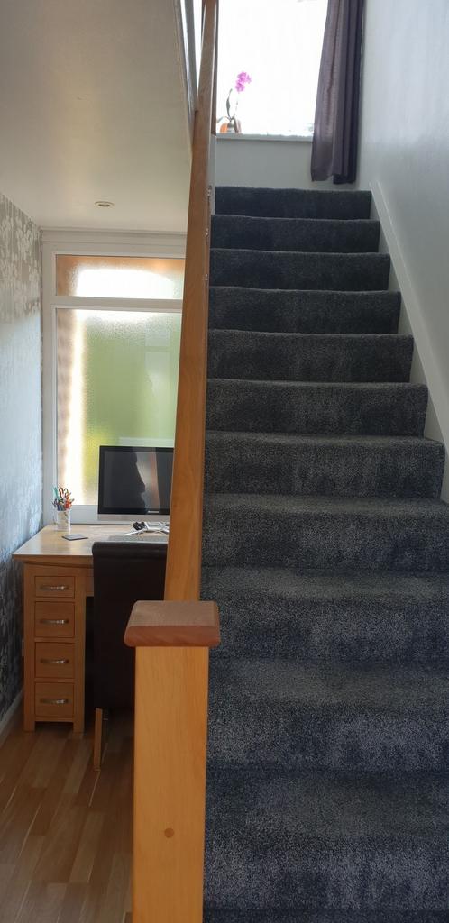 Carpeted staircase with wooden handrail adjacen...