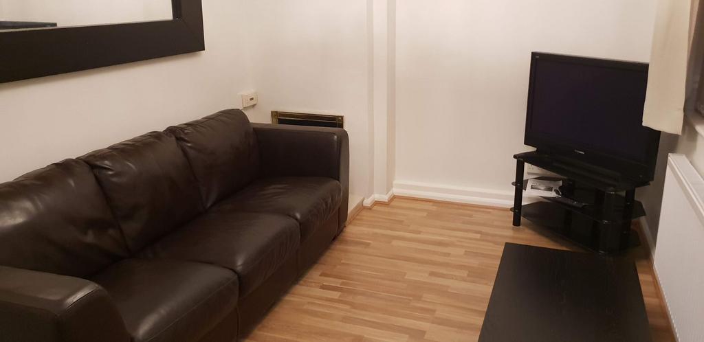 Neat living area with a dark leather sofa, wall...