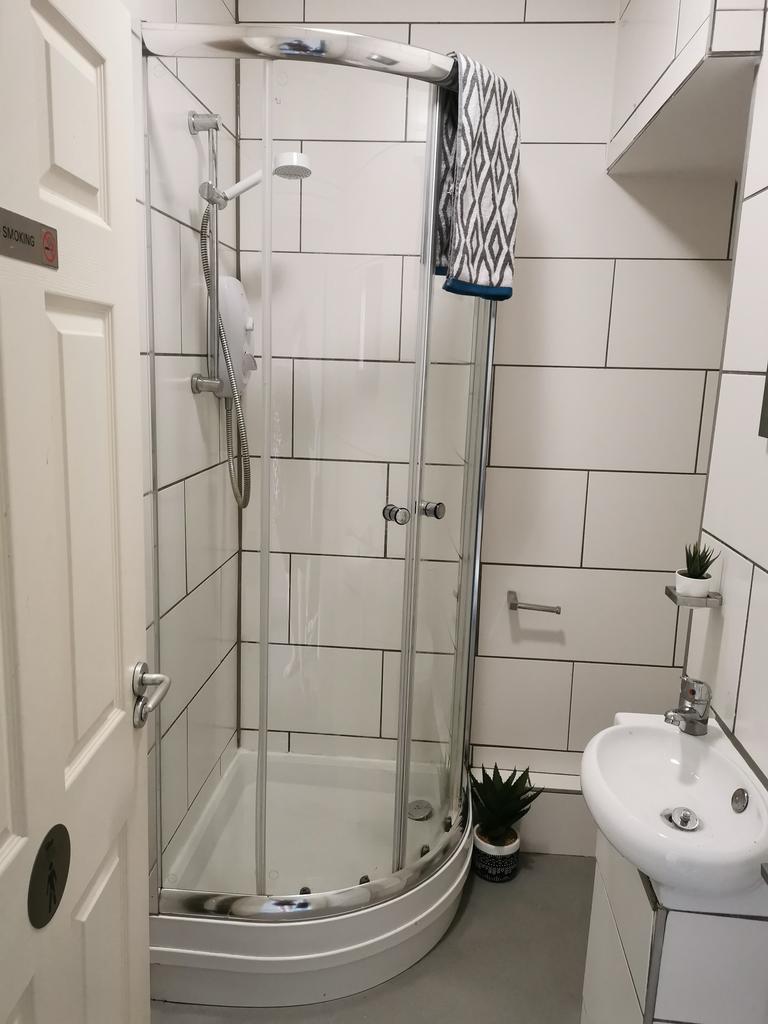 Modern tiled bathroom with a curved glass showe...